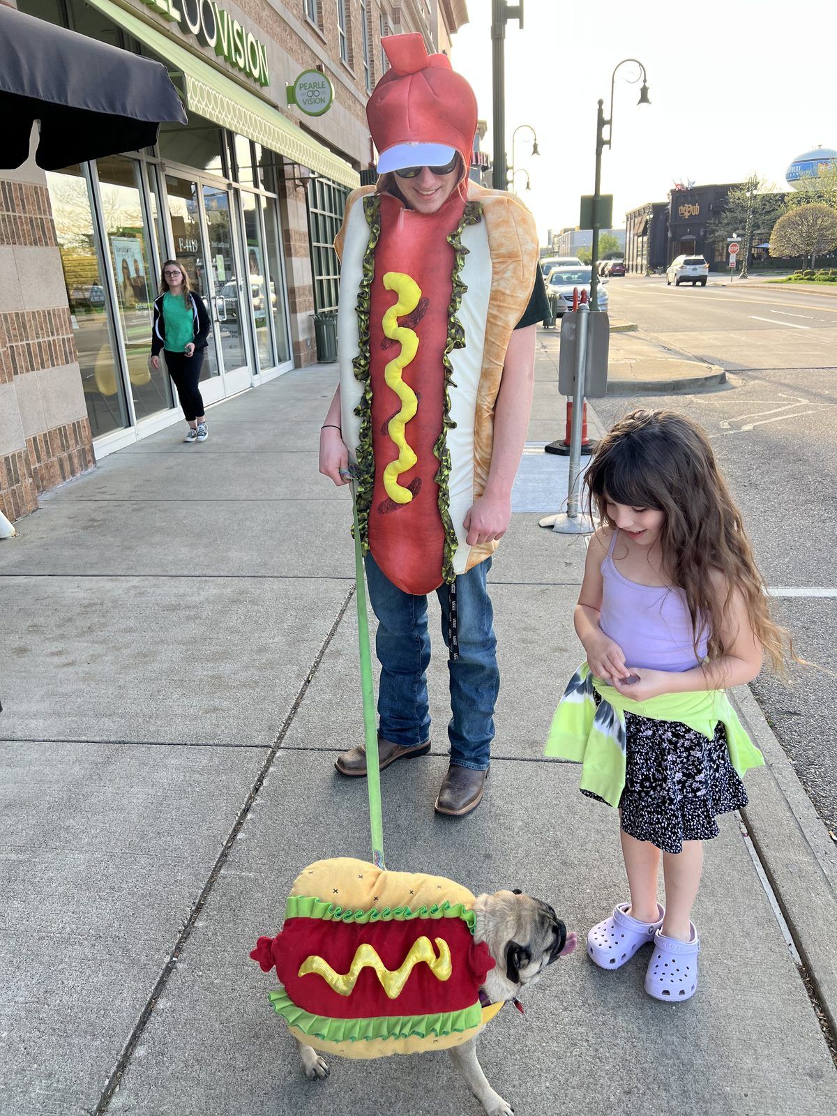 Kid in a hot dog costume walking a pug in a matching hot dog costume at The Greene