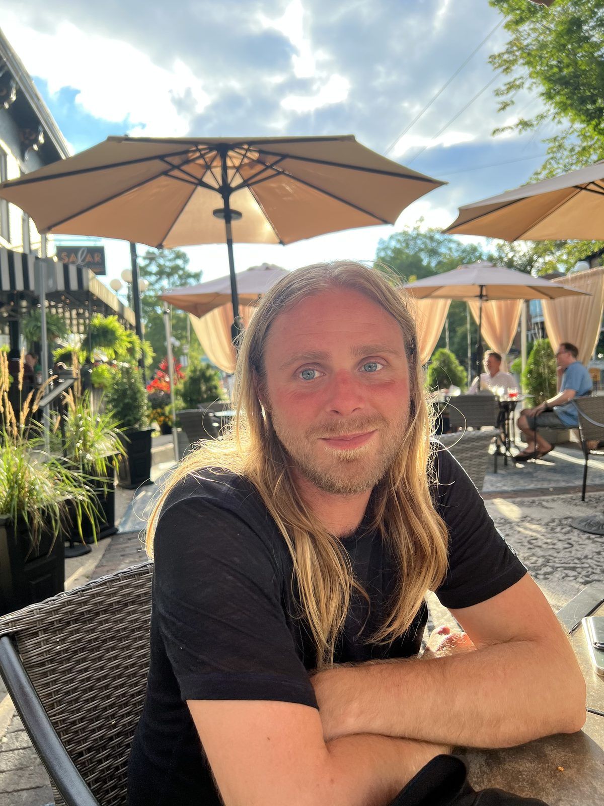 Steve at a downtown patio table under umbrellas on a summer evening