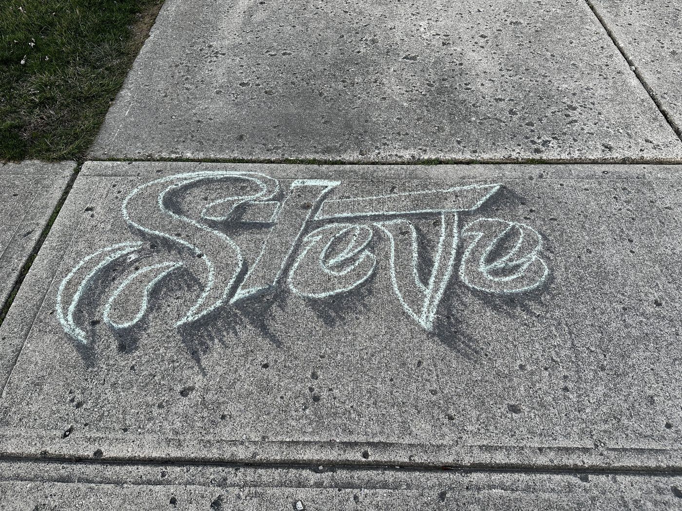 The name Steve written in large chalk script on an Englewood sidewalk