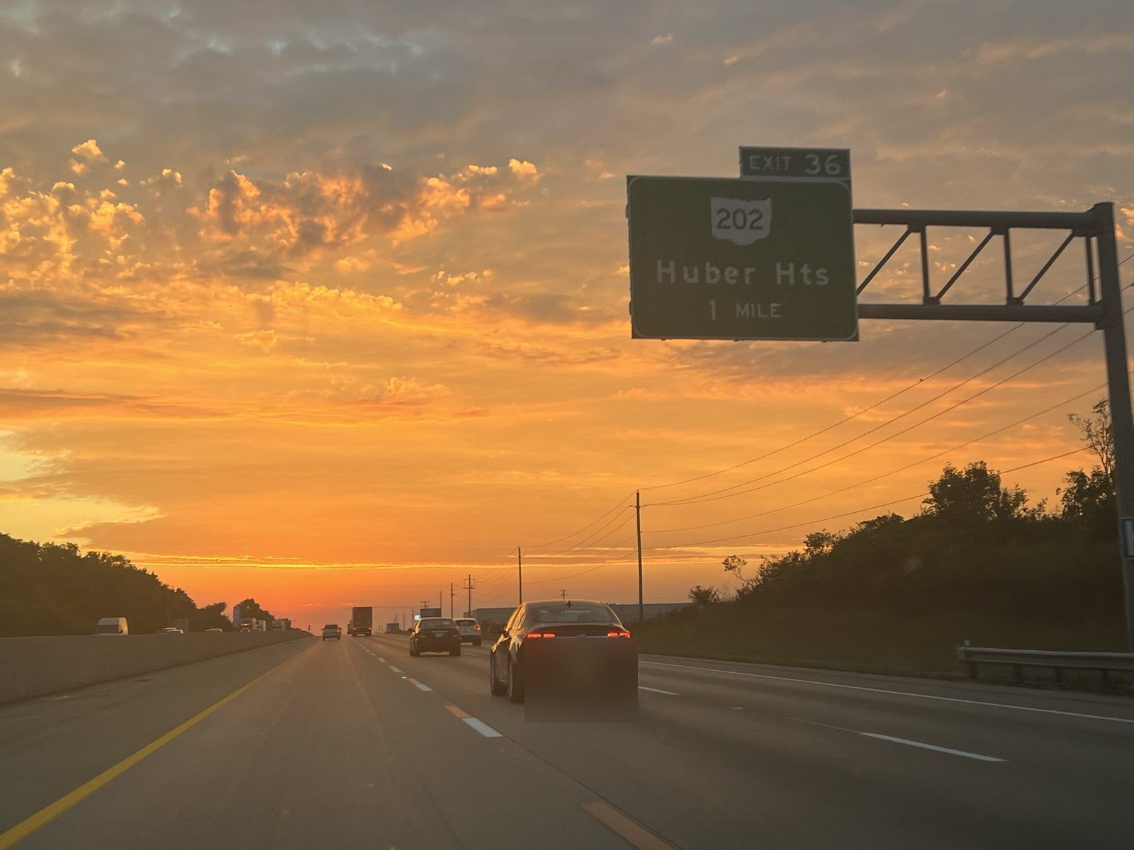 Interstate 70 at sunset, with the overhead sign reading Exit 36, OH-202, Huber Hts, 1 mile