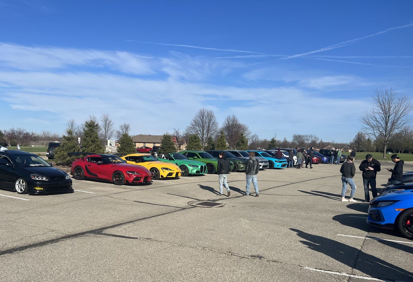 Row of GR Supras and sports cars lined up at a Kettering car meet on a clear morning