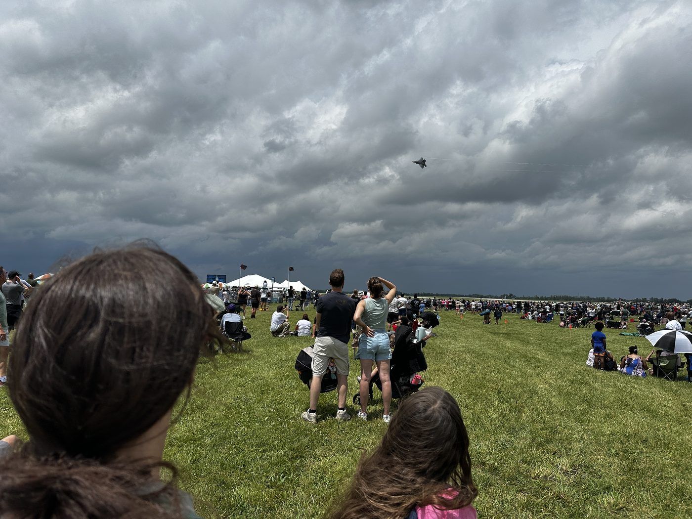 Crowd on the grass watching a fighter jet pass over Dayton International Airport